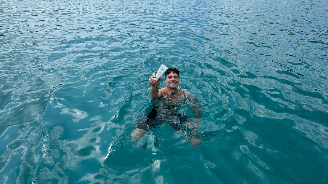 Man in ocean holding sunscreen