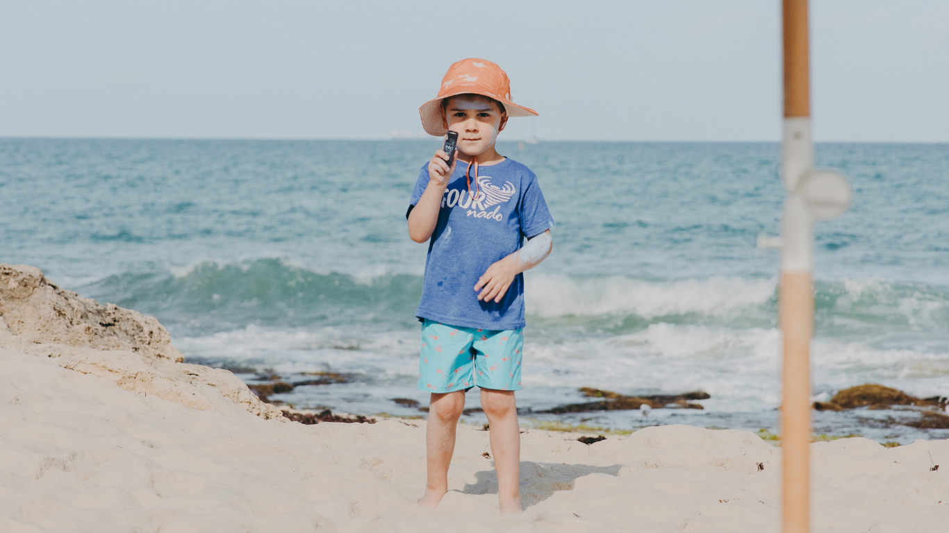 Boy applying sunscreen on the beach