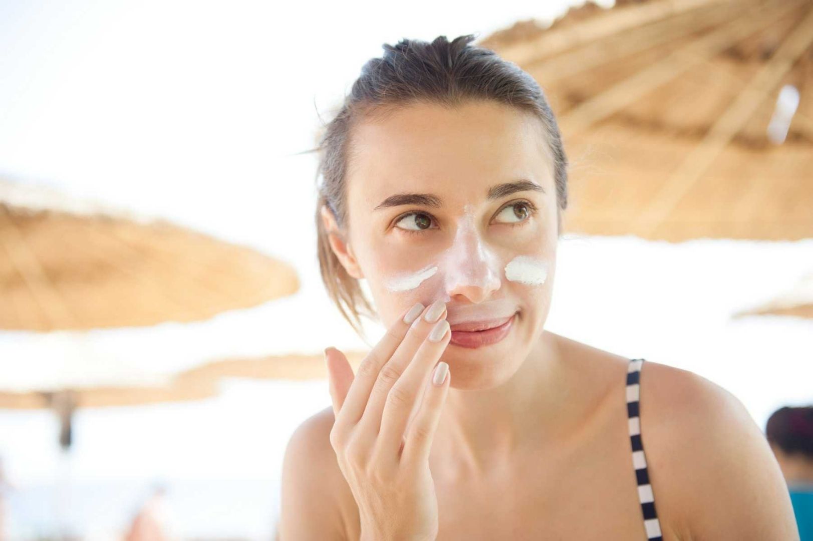 Woman putting sunscreen on her face