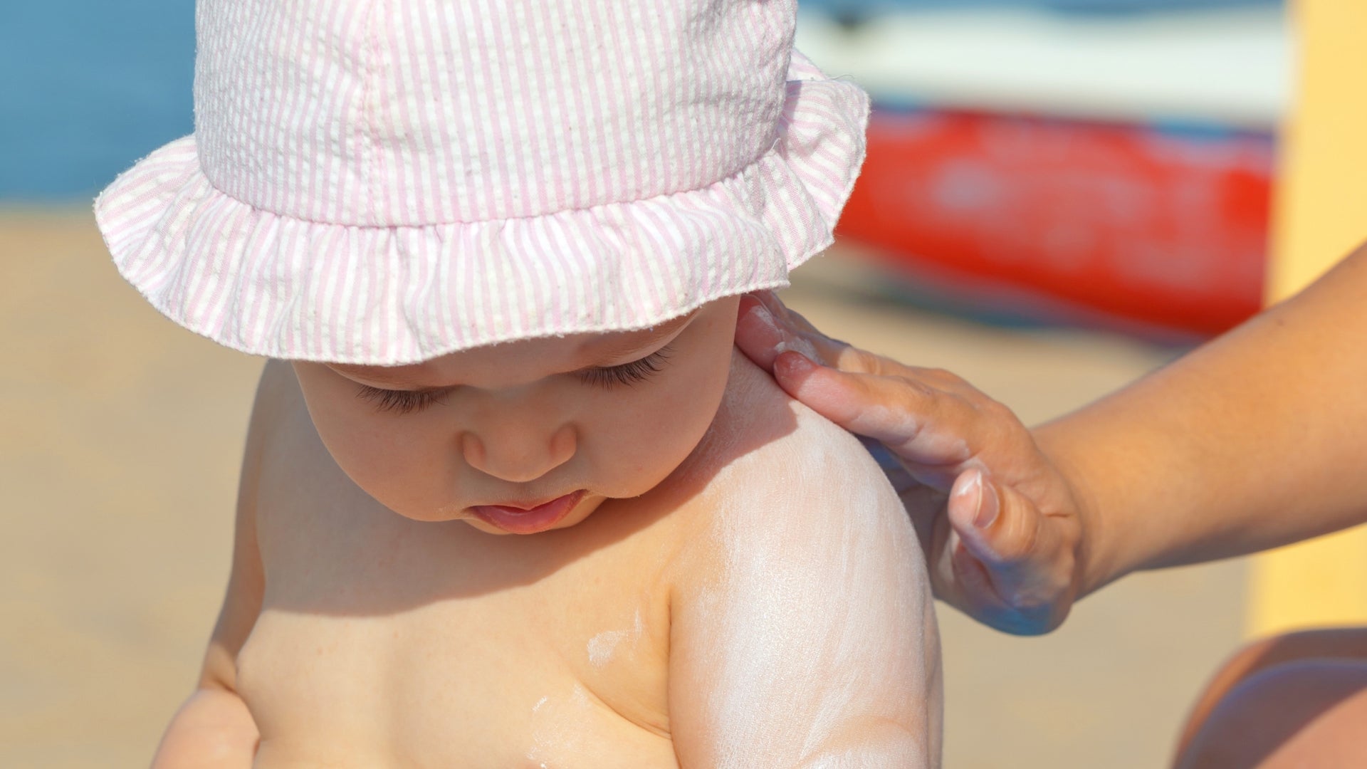 Woman applying sun protection sunscreen to her baby
