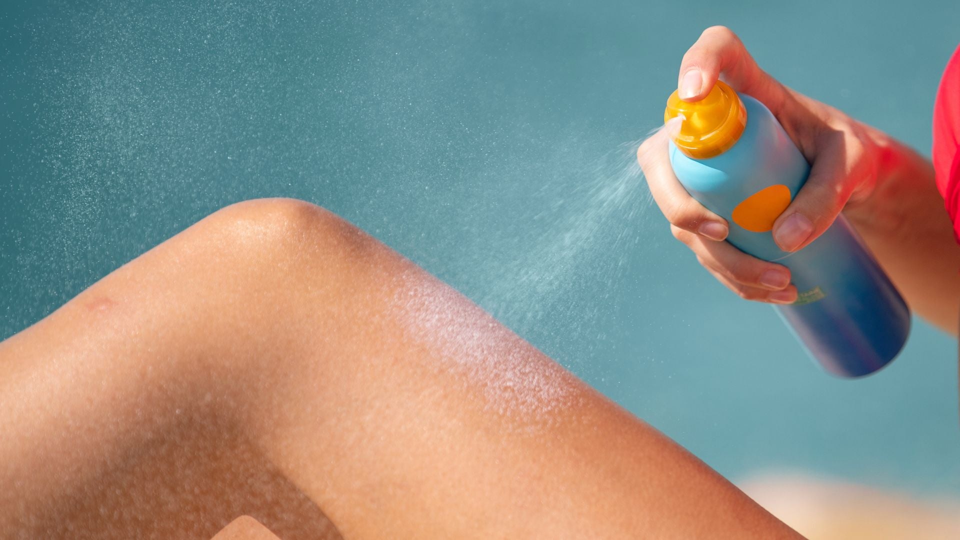 Woman using a sunscreen spray on her leg